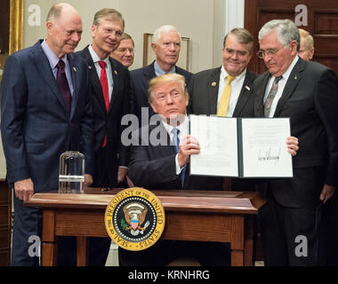 President Donald Trump holds up the Presidential Space Directive - 1 after signing it, directing NASA to return to the moon, alongside members of the Senate, Congress, NASA, and commercial space companies in the Roosevelt room of the White House in Washington, Monday, Dec. 11, 2017. Photo Credit: (NASA/Aubrey Gemignani) Presidential Space Directive - 1 Signing (NHQ201712110008) Stock Photo