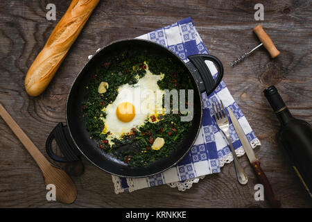 Fried eggs and spinach in a pan Stock Photo