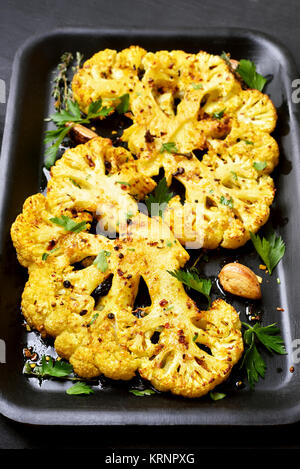 Roasted cauliflower steaks with herbs and spices on baking sheet Stock Photo