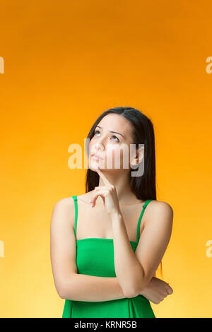 The thinking Chinese girl on yellow background Stock Photo