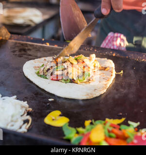 Chef making chicken with grilled vegetable tortilla wrap on street stall. Stock Photo