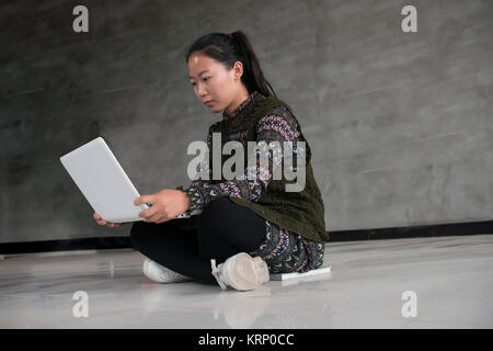 Asian female college students sitting on the floor using laptops Stock Photo
