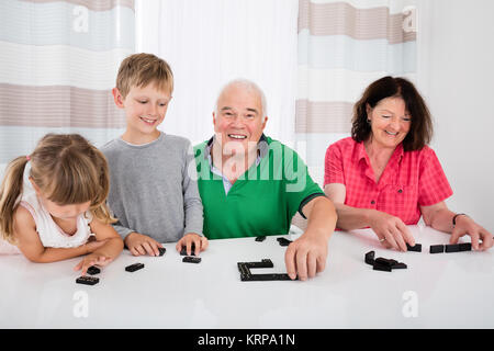 Multi Generation Family Playing Dominoes At Home Stock Photo