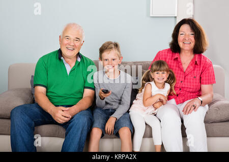 Grandparent And Grandchildren Watching Television Together Stock Photo