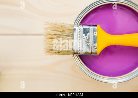 Renowating an appartment. A tin can of fuschsia oil paint with a brush on a light uncolored wooden background. Close up. Top view. Space for your text Stock Photo