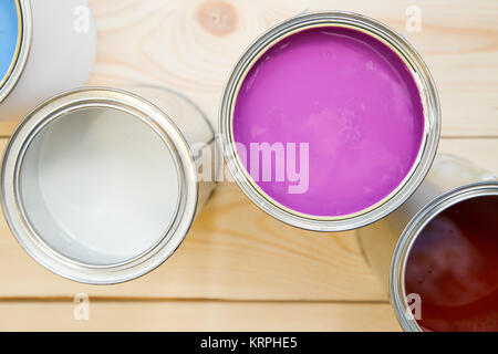 Painting new appartment. Tin cans of fuchsia, white and brown, oil paint on a light uncolored wooden background. Close up. Top view. Space for your te Stock Photo