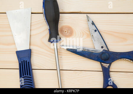 Repairing and construction concept. A set of tools for house repair-a plastering trowel, scissors and screwdriver on a light uncolored wooden backgrou Stock Photo