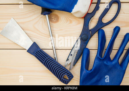 Repairing and construction concept. A set of tools -a plastering trowel, scissors, screwdriver and gloves on a light uncolored wooden background, clos Stock Photo