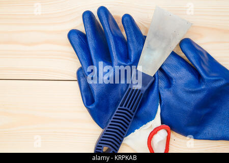 Repairing and construction concept. A plastering trowel and blue latex gloves on a light uncolored wooden background, close up. Top view. Space for yo Stock Photo