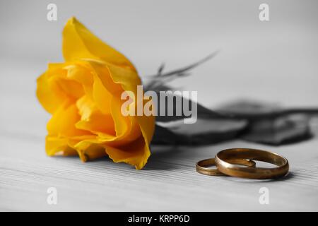yellow rose and wedding rings lie on a table Stock Photo