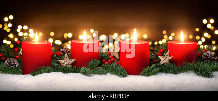 advent decoration with four candle flames,lights,snow,fir branches and wood background Stock Photo