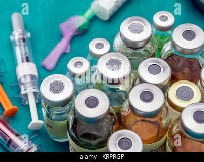 Vials of different size next to syringes at a hospital table, conceptual image Stock Photo