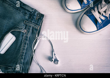 Blue faded jeans and blue sneakers on a white wooden background Stock Photo