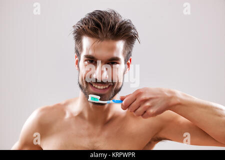 Young handsome man is cleaning his teeth. Stock Photo