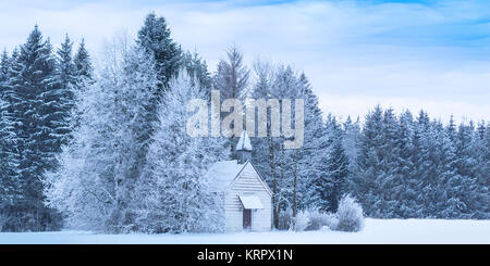 Christmas serene panoramic landscape tiny chapel in snowy frozen forest Stock Photo