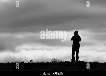 Silhouette on the horizon taking photographs of the views beyond Stock Photo