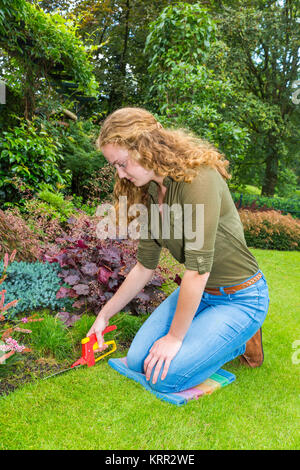 Young european woman working in garden with grass shears Stock Photo