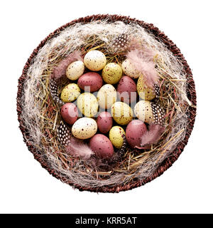 Decorative Easter eggs in basket with hay and Guinea fowl feathers Stock Photo