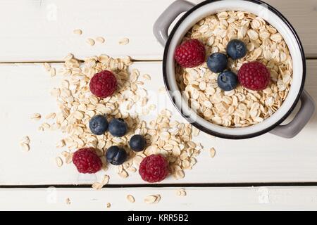 Top down view on small pot of rolled oatmeal with blueberries and raspberries Stock Photo