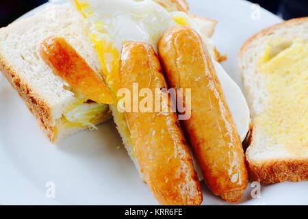 Sausage and fried egg breakfast sandwich on white bread - filter applied Stock Photo