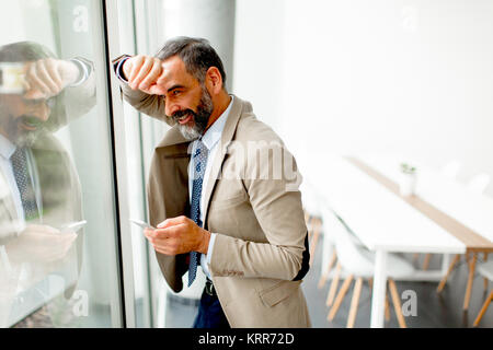 Handsome mature businessman  with mobile phone in the office Stock Photo