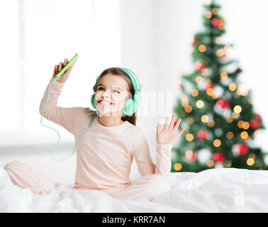 girl with smartphone and headphones at christmas Stock Photo