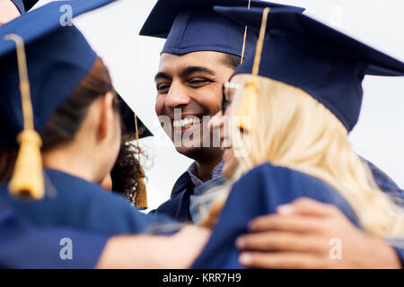 happy students or bachelors in mortar boards Stock Photo