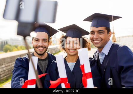 students or graduates with diplomas taking selfie Stock Photo