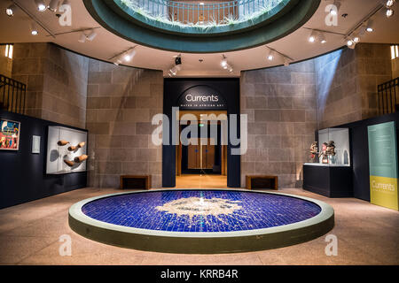 National Museum Of African Art Interior Washington DC | WASHINGTON D.C., United States — A circular blue-tiled fountain marks the entrance to Currents: Water in African Art, an exhibition gallery at the Smithsonian's National Museum of African Art. Woven fish traps, carved masks, and painted panels line the surrounding stone walls of the museum's underground exhibition space on the National Mall. Stock Photo