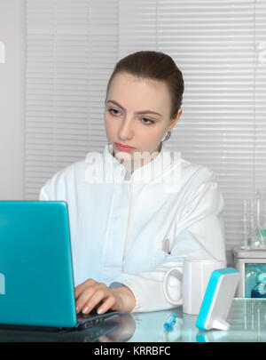Serious attentive female scientist or medic works on portable computer in scientific laboratory or office. Shallow DOF, focus on the face Stock Photo