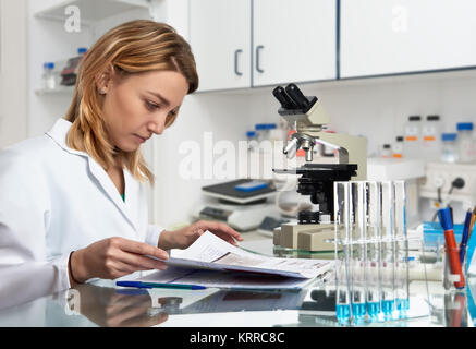 Young European female scientist checks her laboratory journal in the lab Stock Photo