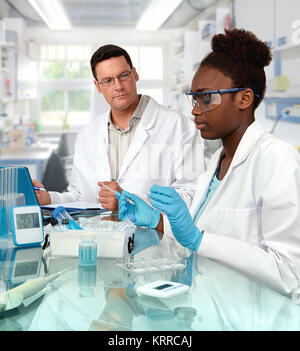 Scientists, senior Caucasian male and young African female, work in the lab. Shallow DOF, focus on the girl. Stock Photo