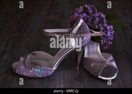 Argentine tango stilettos and lilac flower on dark wooden floor Stock Photo