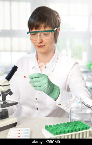 Middle-aged female scientist or tech working with microscope in research facility Stock Photo