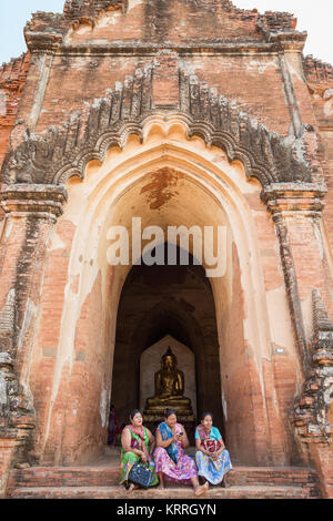 Three older Burmese women sitting in front of the Dhammayangyi Temple in Bagan, Myanmar (Burma), viewed from the front. Stock Photo