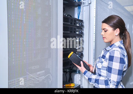female technician working on server maintenance in white server room next to open server rack Stock Photo