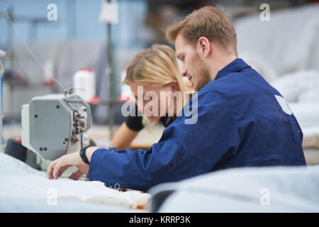 Seamstress is new assigned to a machine in a textile factory, the foreman explains something Stock Photo