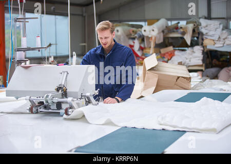 worker in protective clothing in factory using machine Stock Photo
