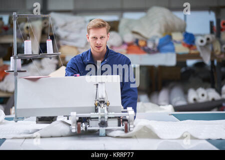 worker in protective clothing in factory using machine Stock Photo