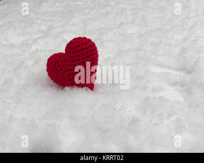 Small red knitted heart lying on the white snow Stock Photo