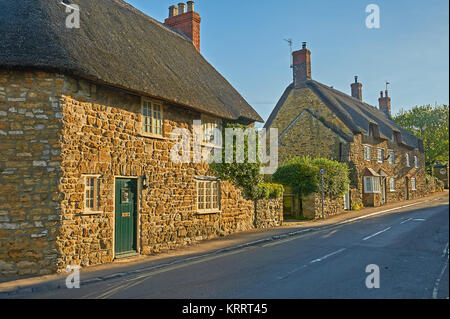 Streetscene in the pretty Dorset village of Abbotsbury, with thatched cottages under a blue sky. Stock Photo