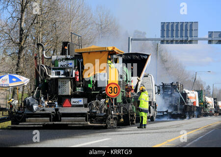 KAARINA, FINLAND - MAY 14, 2015: Machine laying asphalt concrete and unidentified workmen at road works. Hot mix asphalt concrete is produced by heati Stock Photo