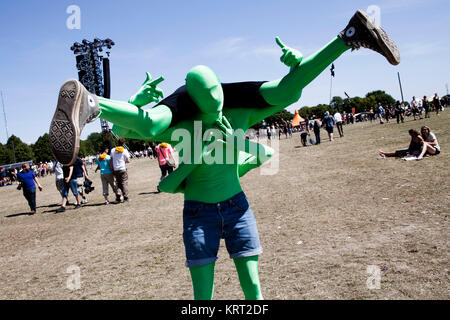 At Roskilde Festival it's tradition that people dress up and disguise in many ways. Here are two guys are having fun in neon-green spandex whole body costumes. Denmark 2013. Stock Photo