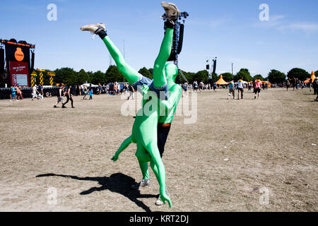 At Roskilde Festival it's tradition that people dress up and disguise in many ways. Here are two guys are having fun in neon-green spandex whole body costumes. Denmark 2013. Stock Photo