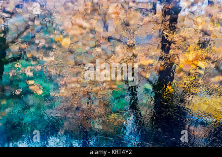 rain in the park glass wet surface with reflection, rain drops on the drenched window glass, background window in the autumn park, autumnal rainy land Stock Photo