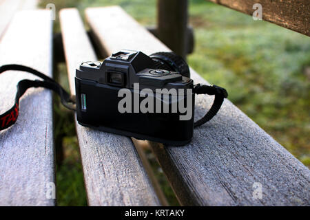 Old camera on wooden bench an eraly frozen winter morning Stock Photo