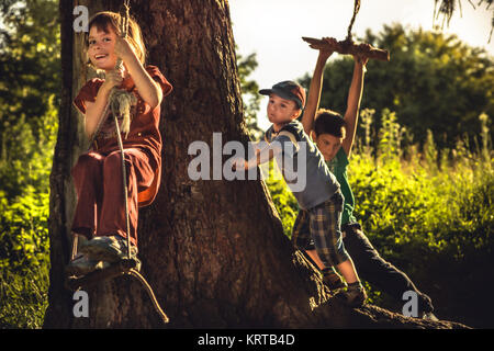 Cheerful children having fun outdoors in forest during summer holidays in countryside symbolizing happy carefree childhood Stock Photo