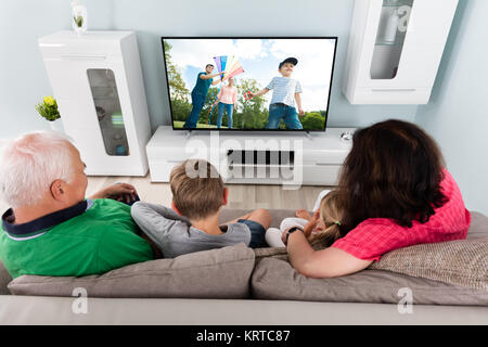 Grandparent And Grandchildren Watching Television Together Stock Photo