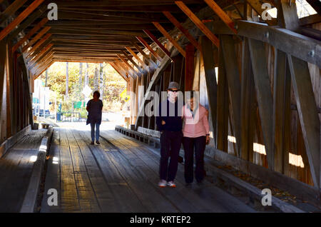 Couple posing on The Poland Covered Bridge, also known as the Junction Covered Bridge over the Lamoille River near Jeffersonville, Vermont, USA Stock Photo