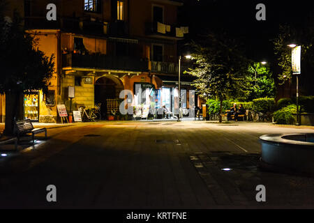 Late night at Garibaldi Square, the main town square of Monterosso Al Mare, Cinque Terre, with a few locals in front of a lighted shop Stock Photo